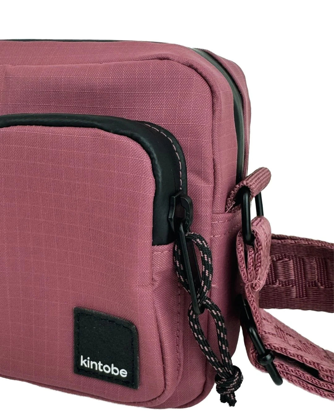 Lille skuldertaske med plads til telefon og pung: 18x12x4.5 cm | 1 liter. Tasken af lavet af genbrugsmaterialer, og er i en lilla/rødlig farve.