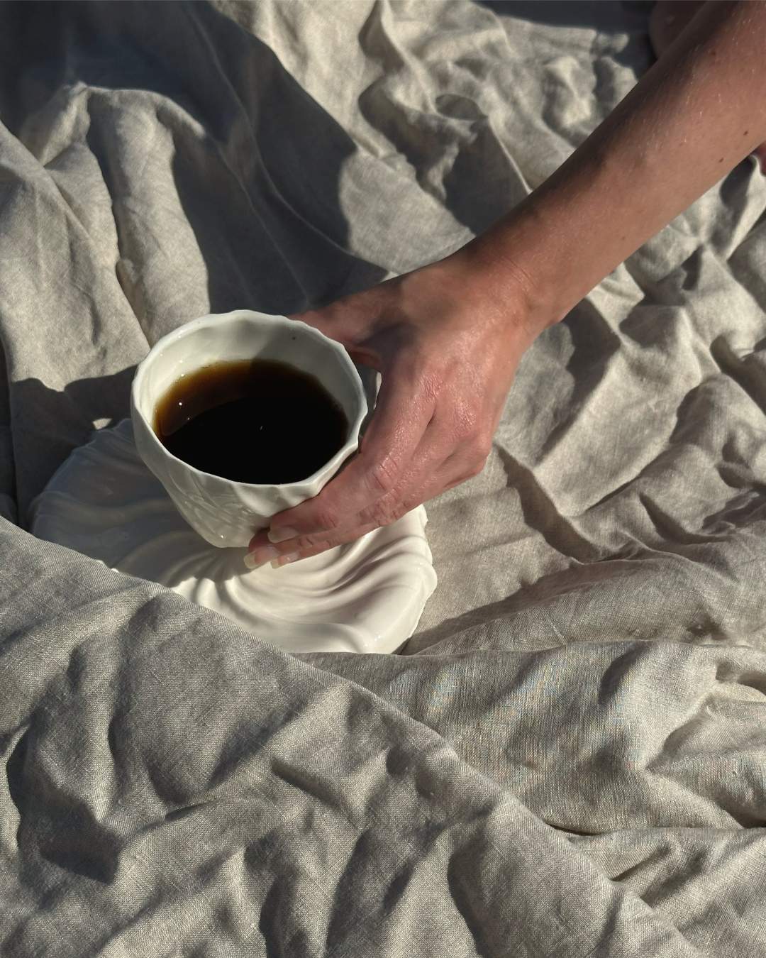 Håndlavet hvid porcelænskop fra Atelier Marée, inspireret af havets bølgede sandbund, rummer 240 ml.