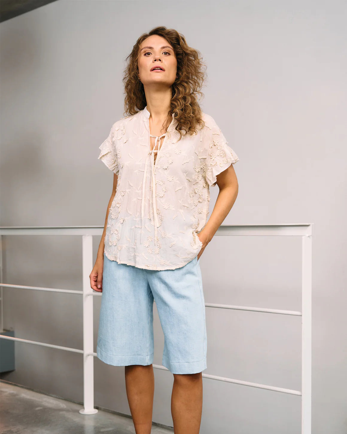 Model iført Britt Blouse – feminin sommerbluse med 3D-blomster og smalle stropper i 100% bomuld