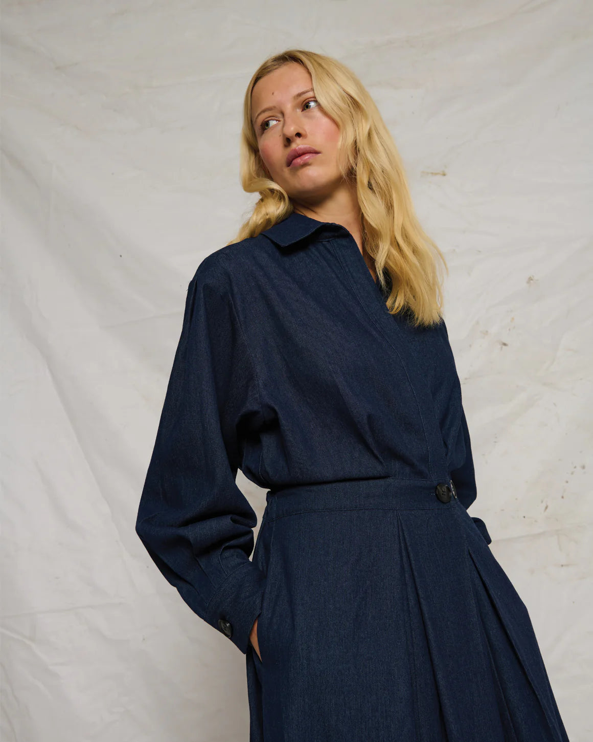 Charlotte Dress – langærmet skjortekjole i mørk marine denim med v-hals, markeret talje og knapdetalje i siden.