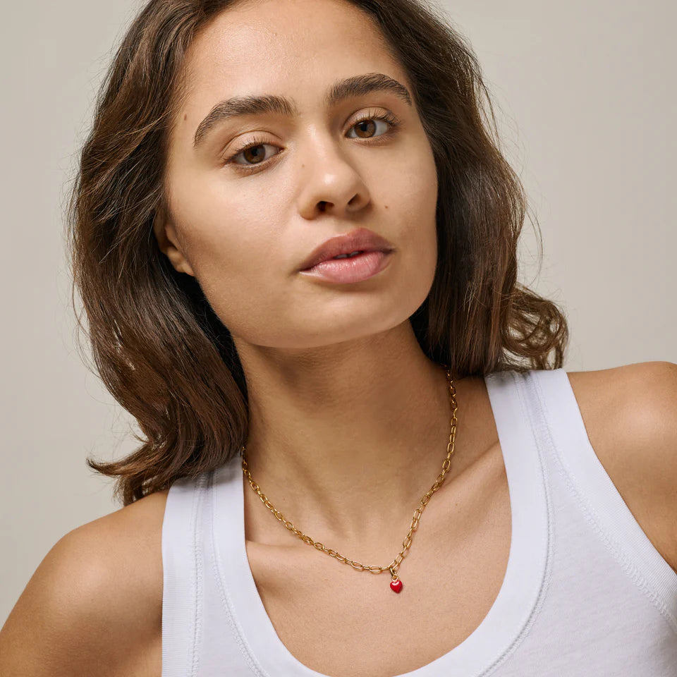 Guld charms vedhæng formet som rødt hjærte.