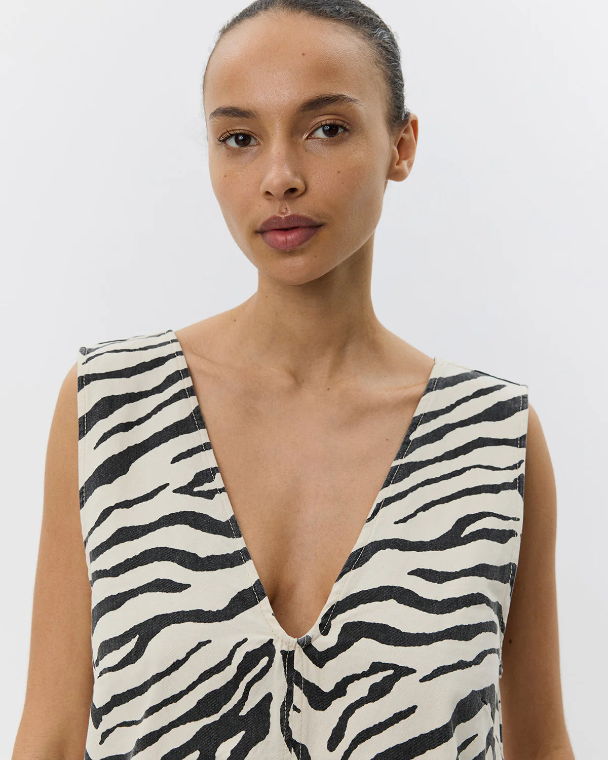 Mini kjole uden ærmer med zebraprint. Der er v-hals foran og bagpå, og det er en perfekt kjole til sommer, men kan også sagtens bruges om vinteren med lag-på-lag.