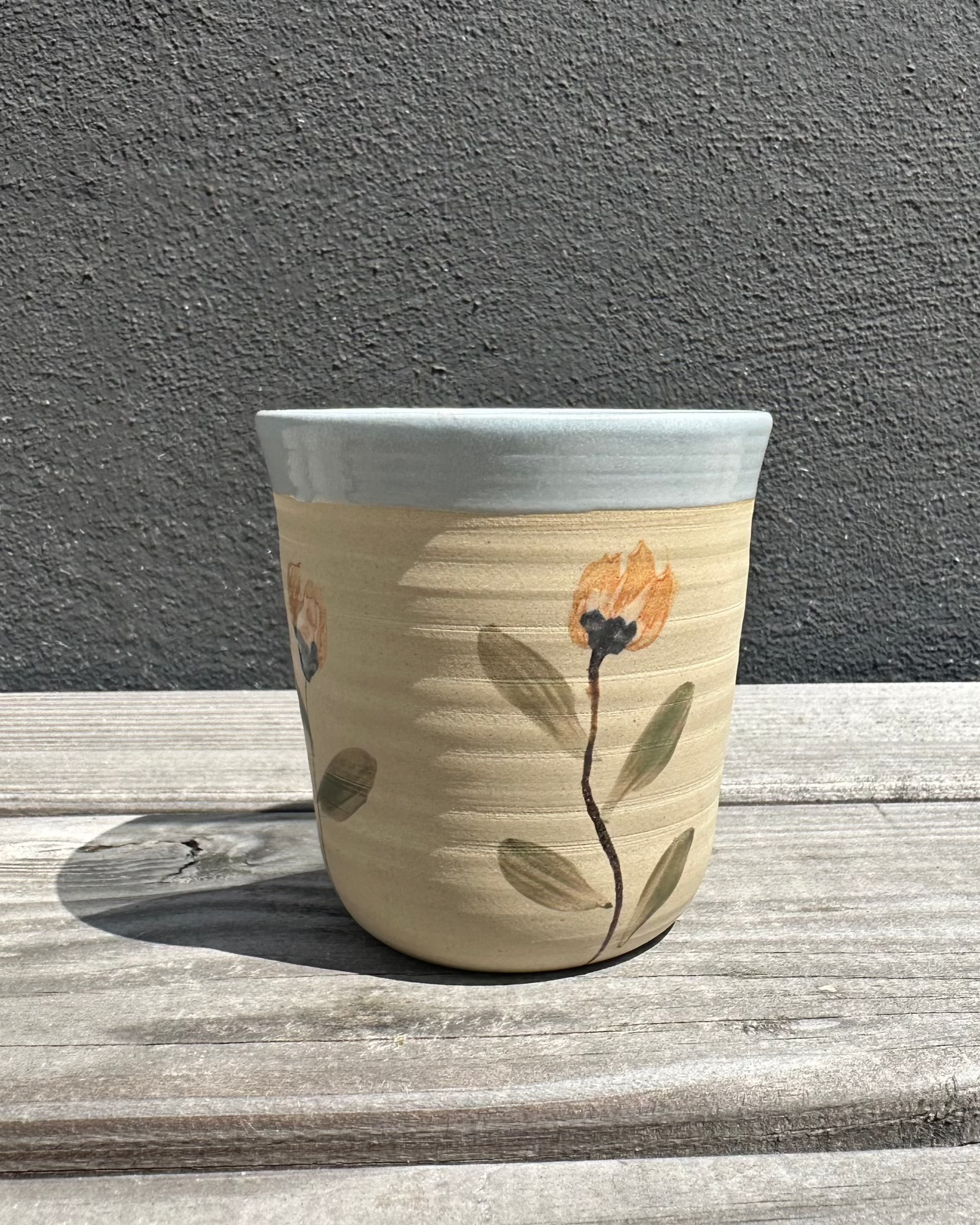 Høj keramikkop med Mild Blomst-design og blå kant, hånddrejet og håndmalet af Stine Mei.