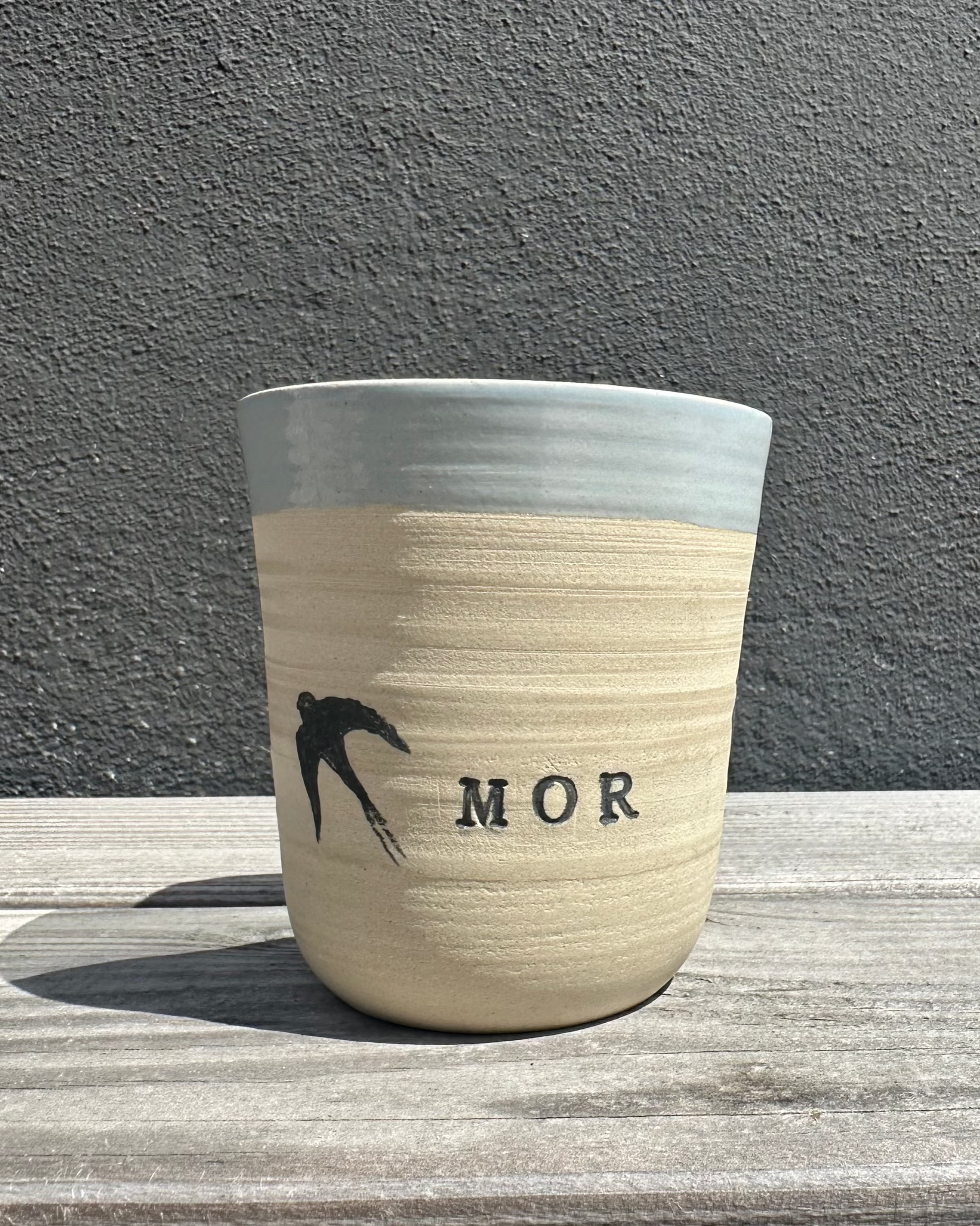 Høj keramikkop med svaler og teksten "FARMOR", hånddrejet og håndmalet af Stine Mei.