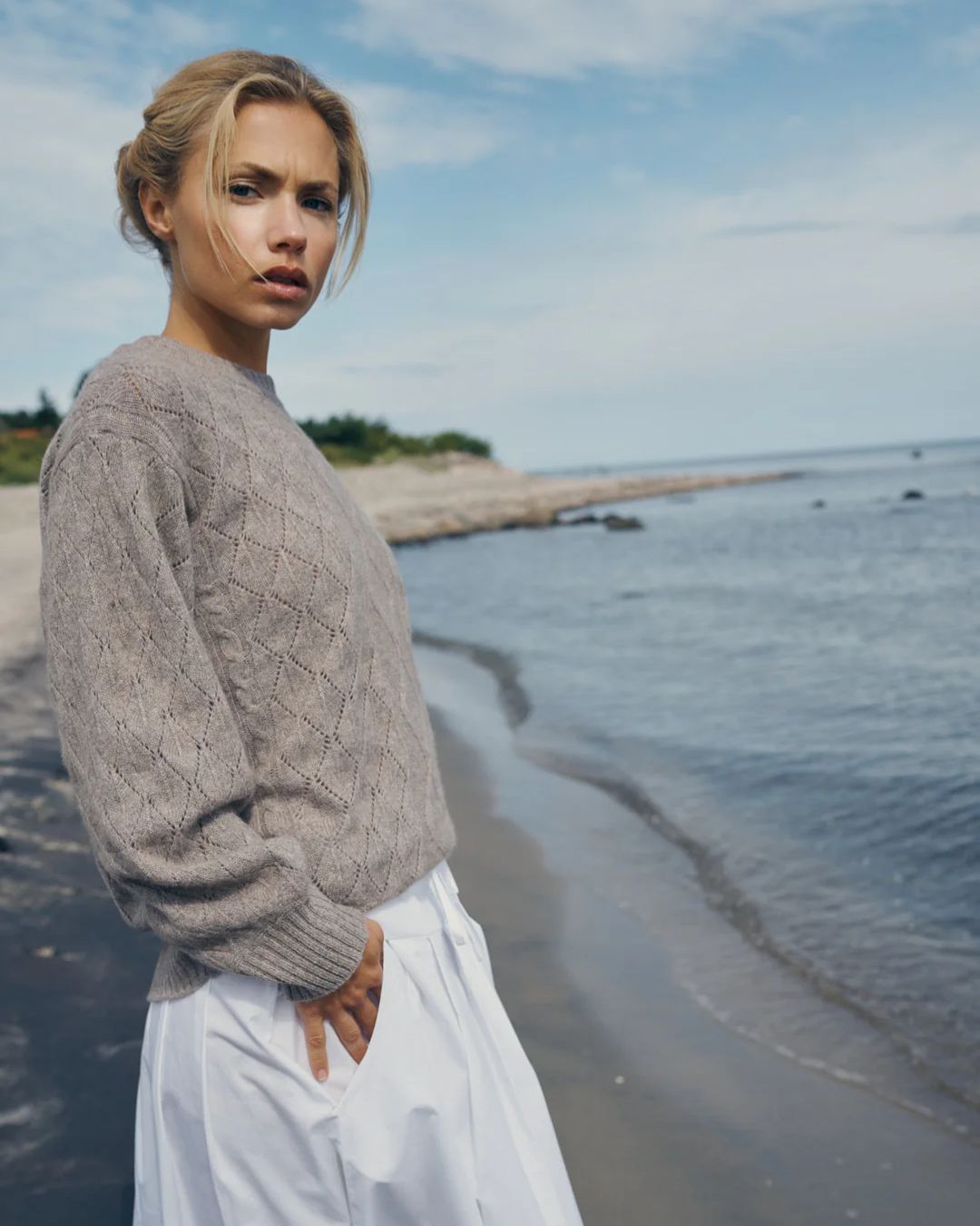 Blød og elegant cashmere striktrøje i sandfarve fra Care By Me – klassisk kabelstrik med rund hals og raglanærmer.