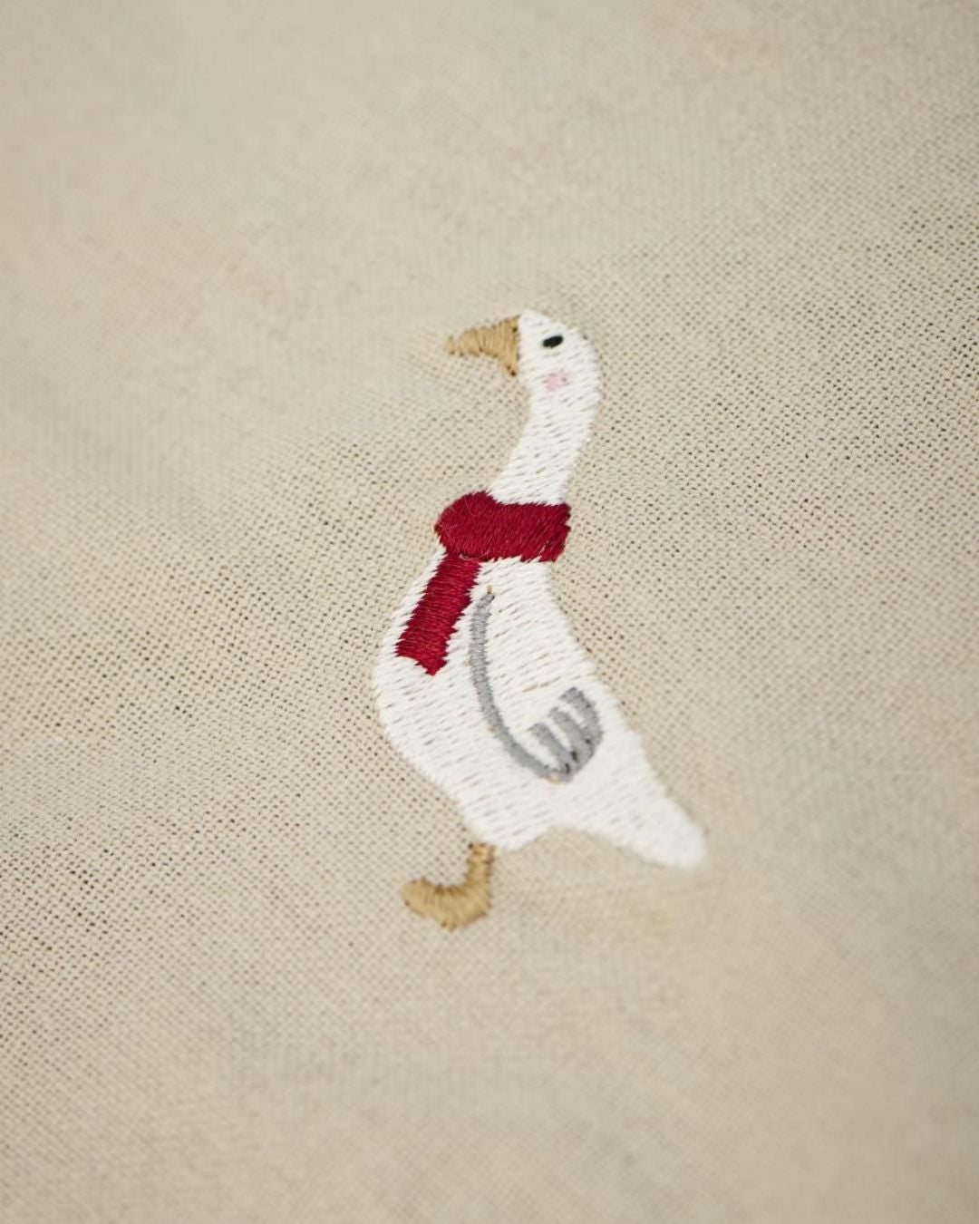 Juledug med broderede julemotiver på hørfarvet baggrund.