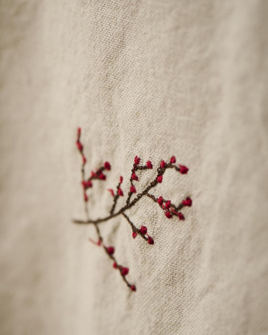 Juledug med broderede julemotiver på hørfarvet baggrund.