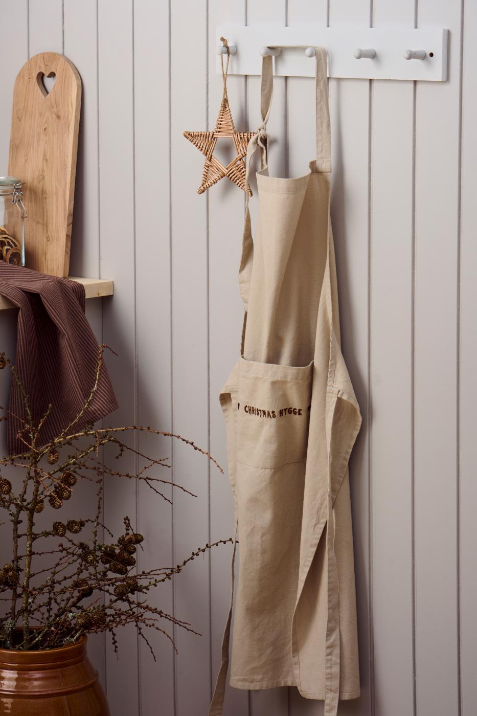 Naturfarvet bomuldsforklæde med brunt “Christmas Hygge”-broderi på frontlommen – køb hos butikalrum.dk.