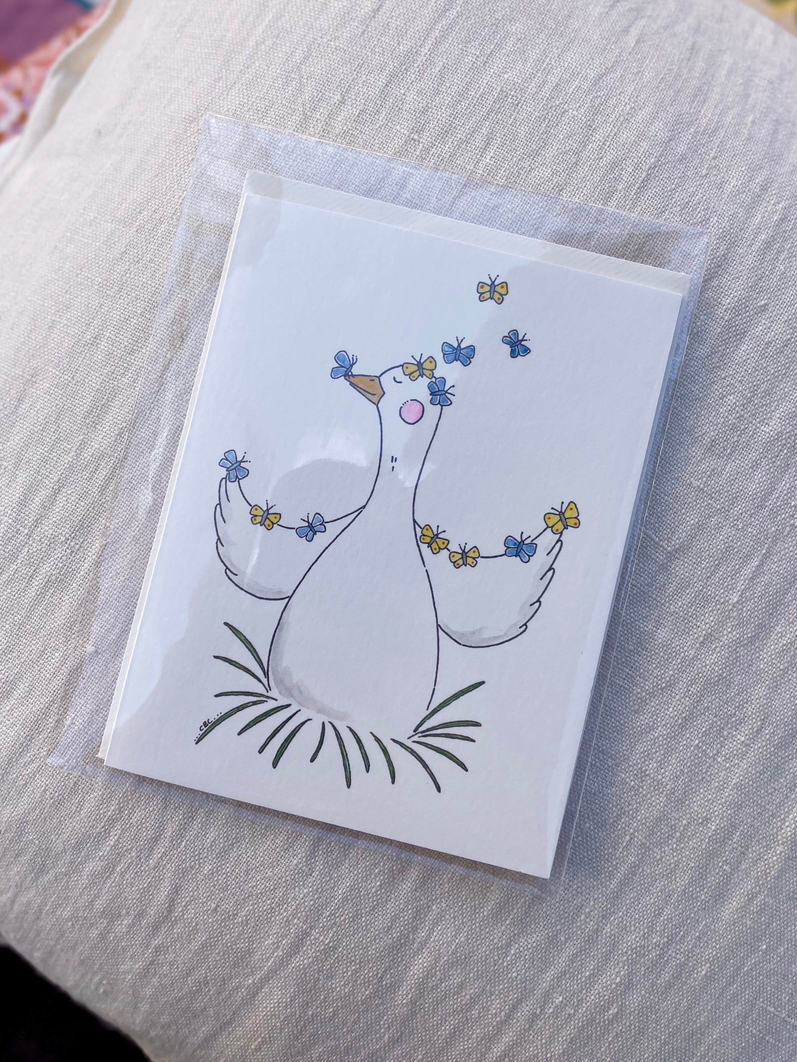 A6 kort med gås omgivet af sommerfugle, illustreret af Cecilie Birk Carmona – køb hos Butik Alrum på Amager eller online på butikalrum.dk.