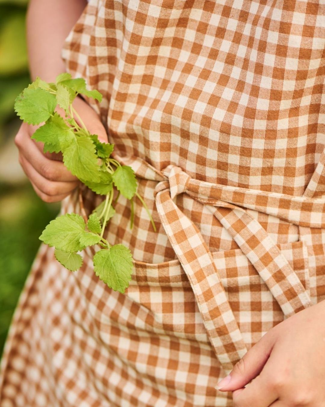 forklæde med brune tern og lomme – klassisk og praktisk design, perfekt til madlavning og bagning.
