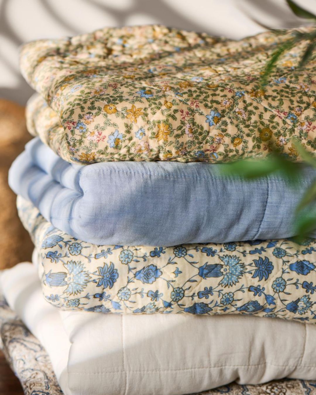 Vattæppe med blomsterprint i gule nuancer med blå og lyserøde blomster – dekorativt og hyggeligt til seng eller sofa.