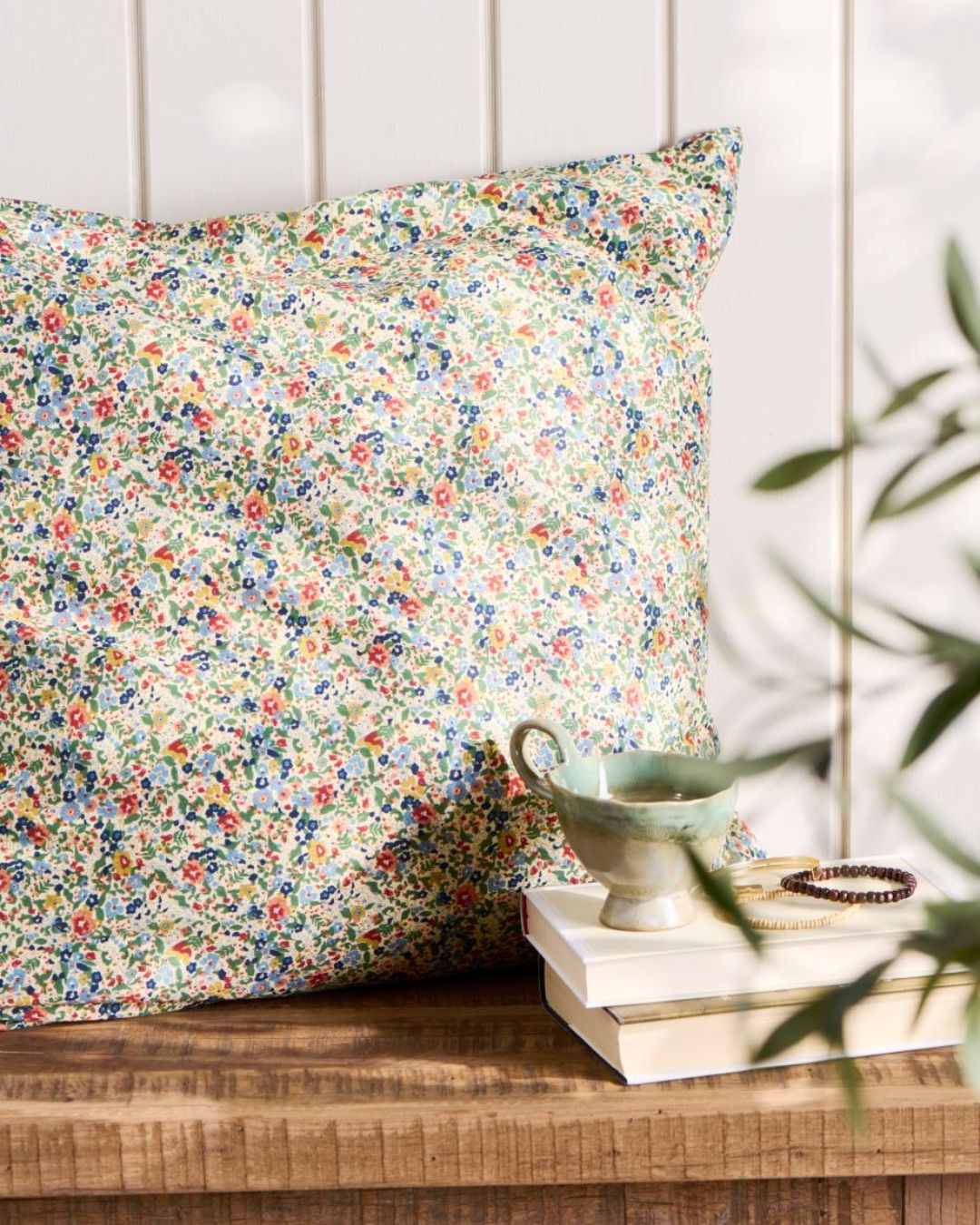 Pude 60x60 cm med blomsterprint i blå, grøn og rust – dekorativ og hyggelig til sofa eller seng.