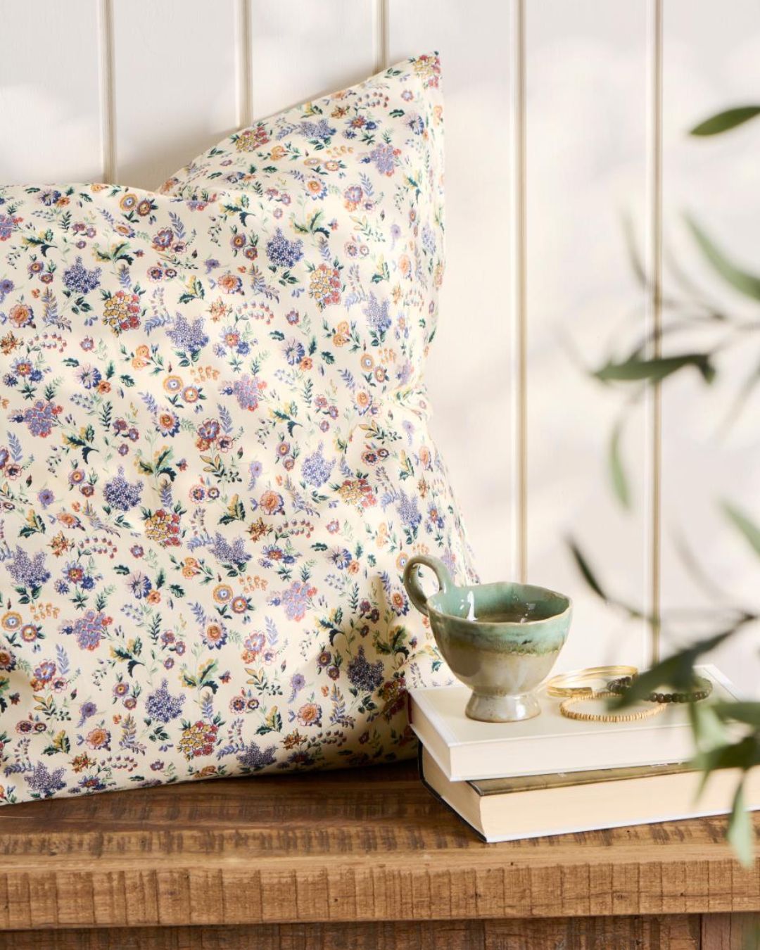 Pude 60x60 cm med blomsterprint i lilla og brun – dekorativ og hyggelig til sofa eller seng.