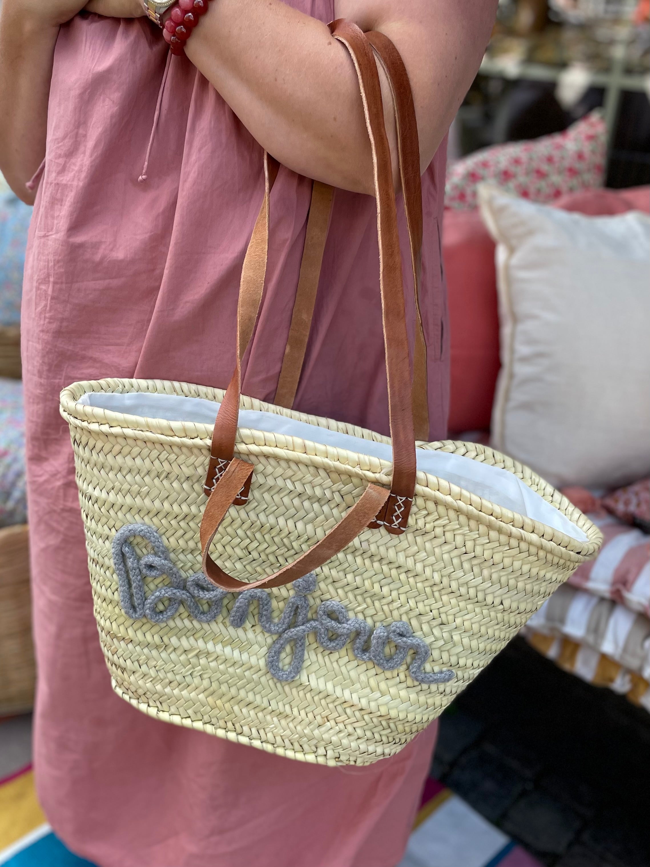 Lille flettaske med brune hanke og grå Bonjour tekst samt praktisk lukkepose indeni – køb hos Butik Alrum på Amager eller online på butikalrum.dk.
