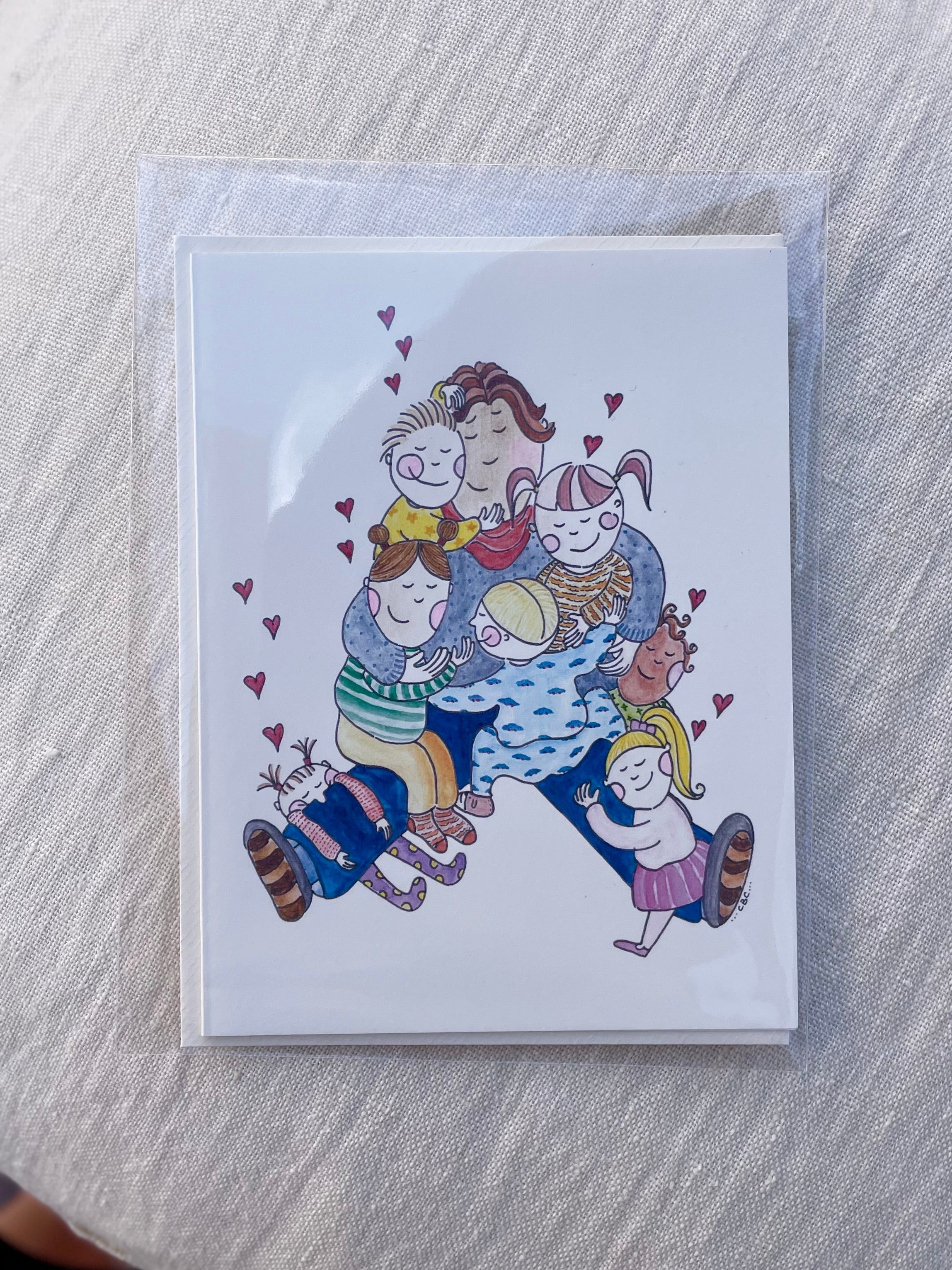 A6 kort med illustration af en pædagog sammen med børn, tegnet af Cecilie Birk Carmona – køb hos Butik Alrum på Amager eller online på butikalrum.dk.