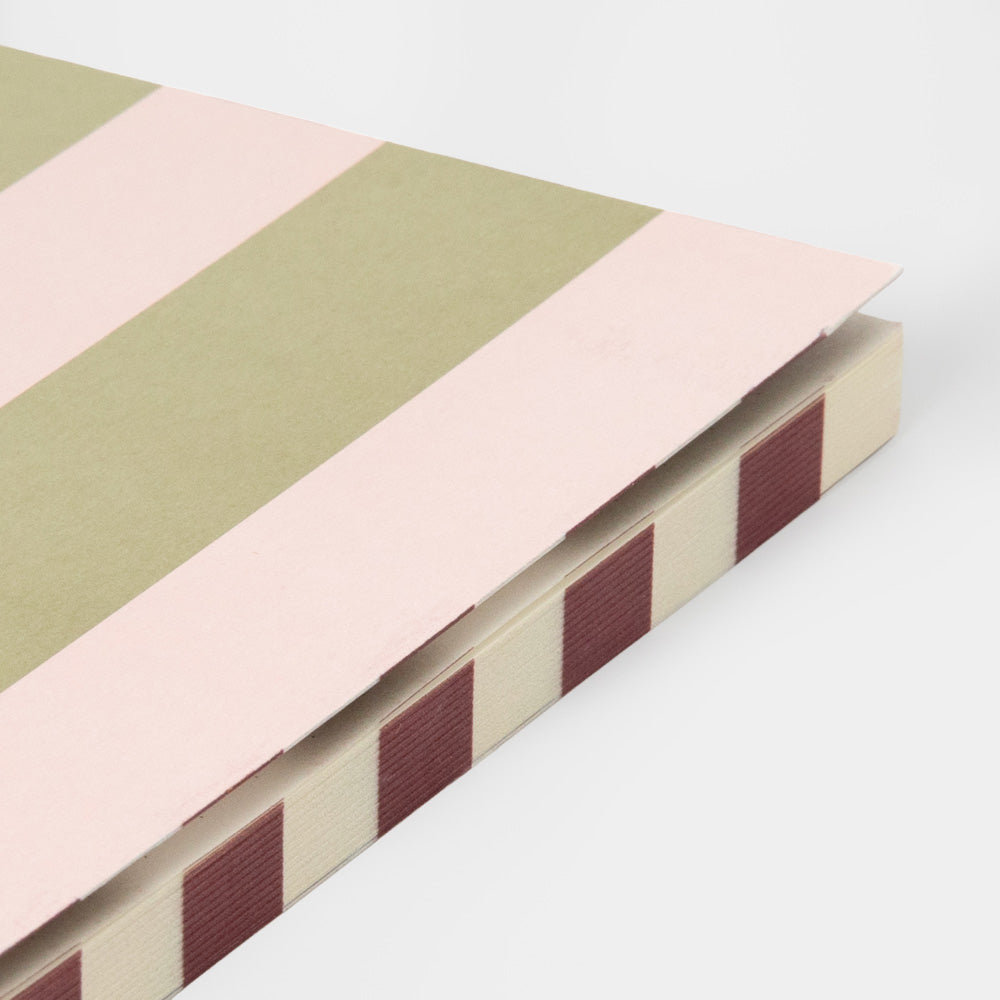 Pink/Green A6 notesbog med blødt omslag i pastelrosa og grønne striber, 192 linjerede sider og datofelt – køb hos butikalrum.dk.