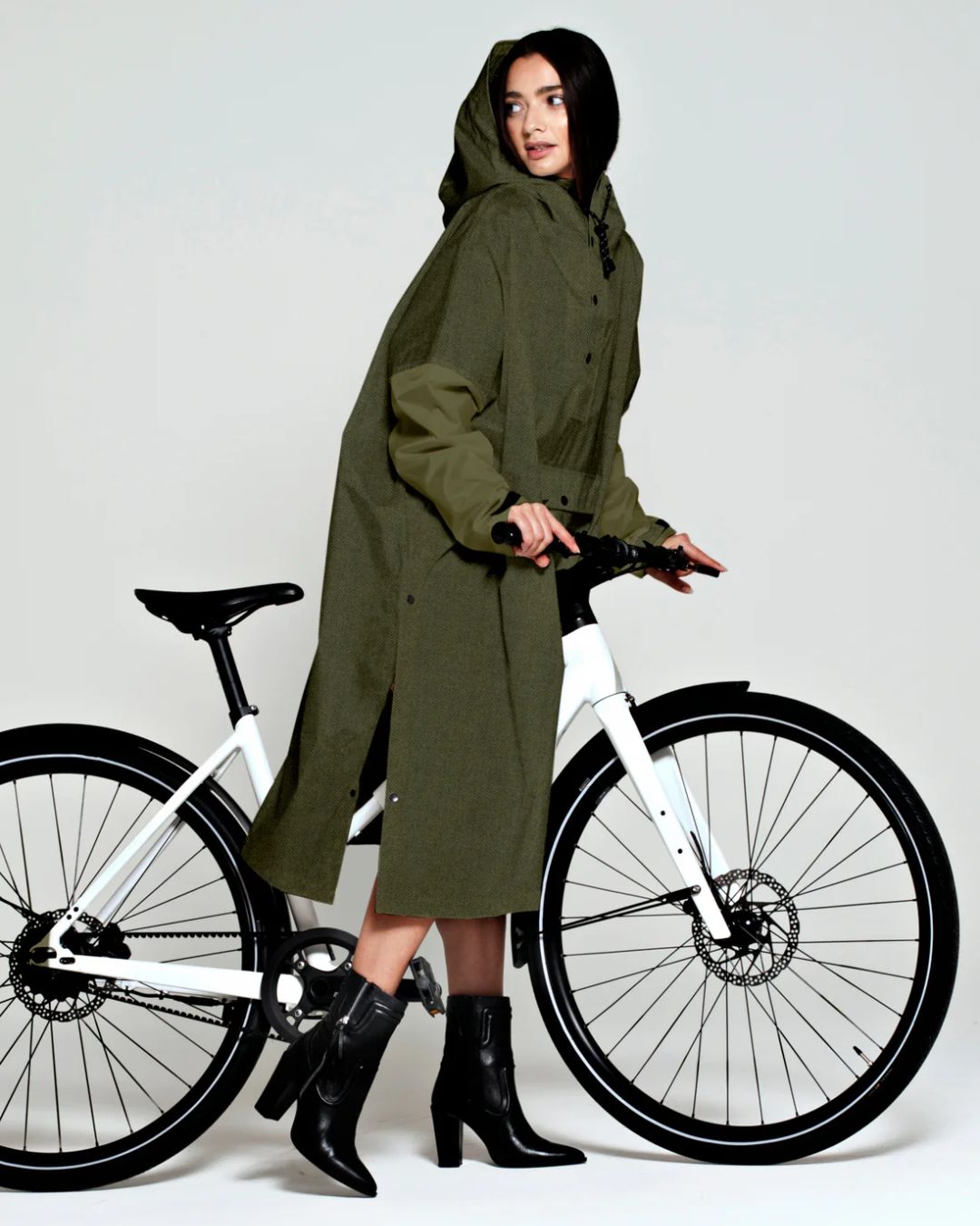 Rainkiss Poncho i Herringbone Green – vandtæt og cykelvenligt design med ekstra længde, der holder lårene tørre i regnvejr.