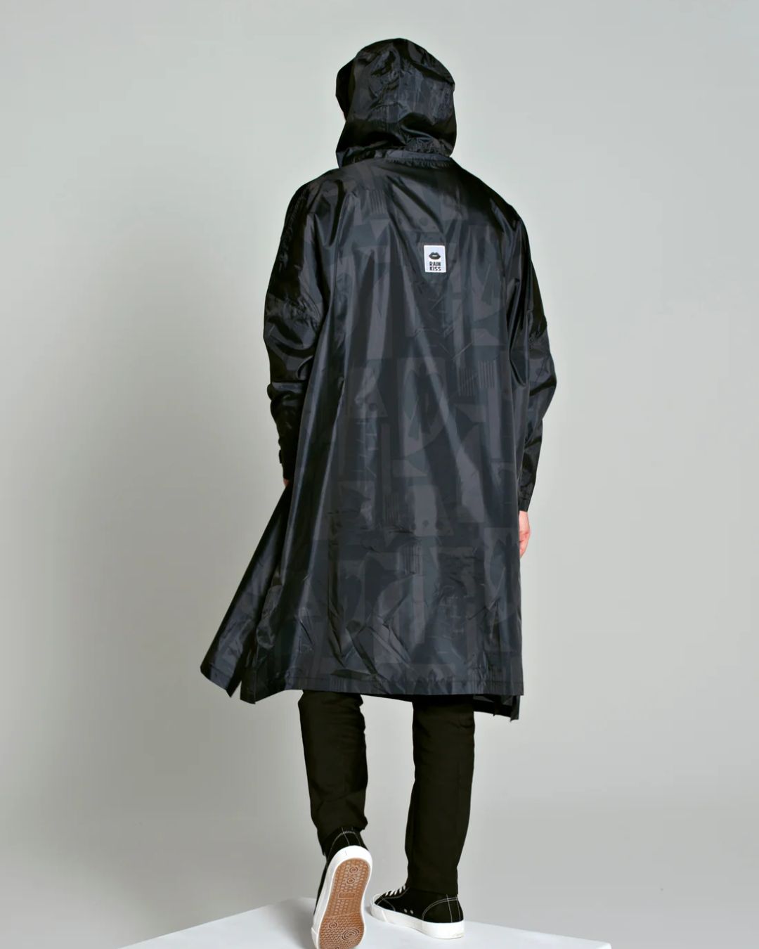 Rainkiss Poncho i back to black art camo – vandtæt og cykelvenlig unisex-regnponcho med ekstra længde, der holder lårene tørre i regnvejr.