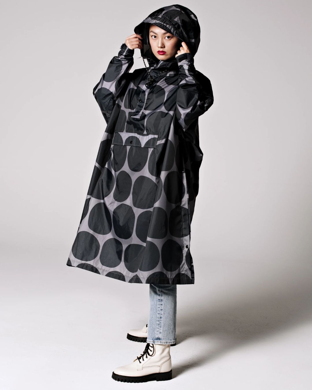 Rainkiss Poncho i Black Polka – vandtæt og cykelvenlig unisex-regnponcho med ekstra længde, der holder lårene tørre i regnvejr.