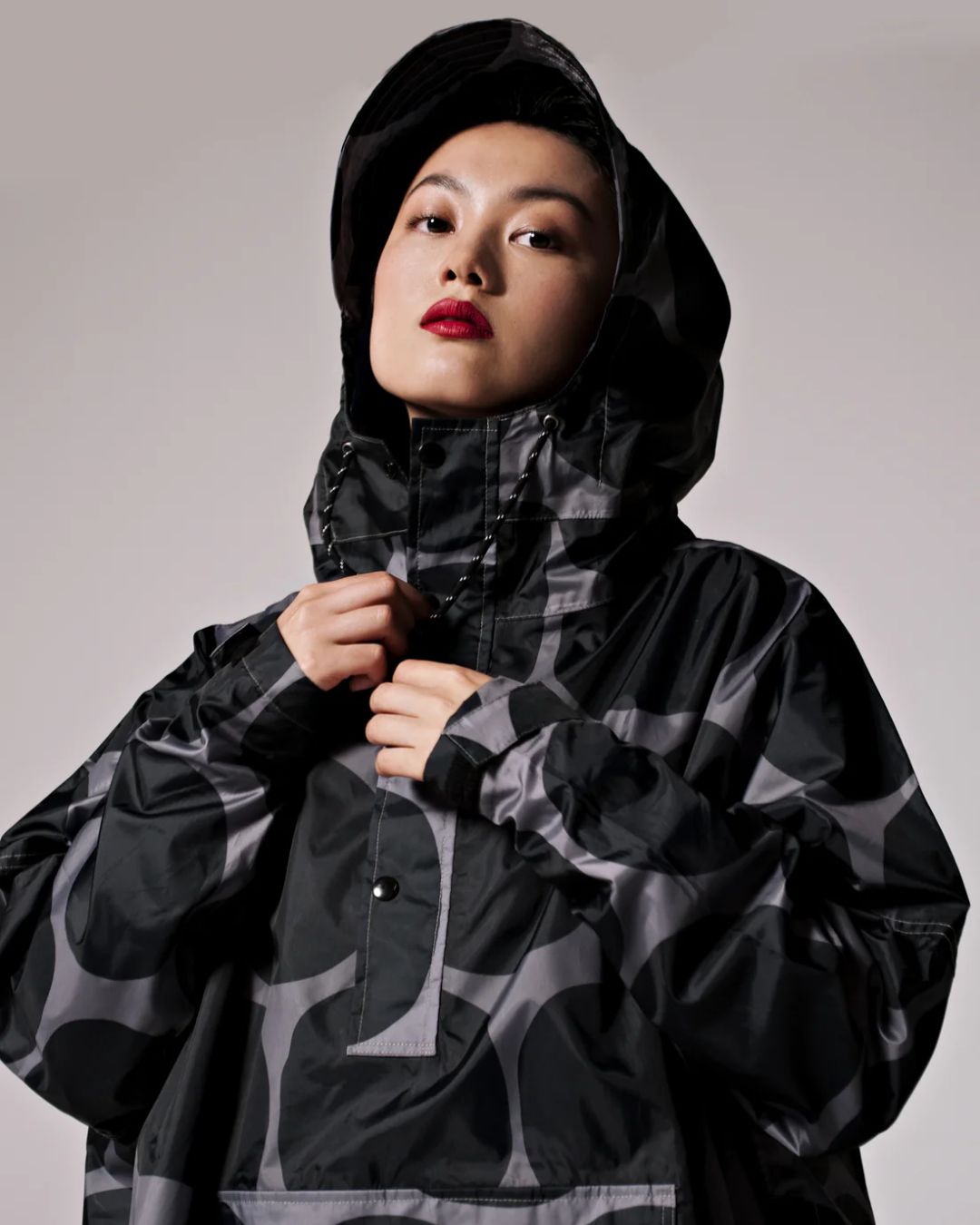 Rainkiss Poncho i Black Polka – vandtæt og cykelvenlig unisex-regnponcho med ekstra længde, der holder lårene tørre i regnvejr.