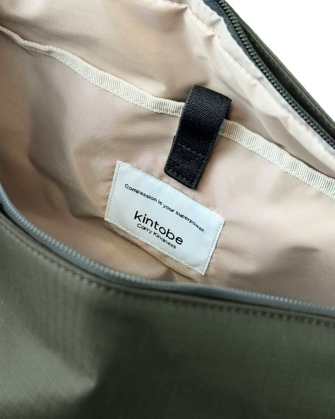 Grøn tote bag taske fra Kintobe i grøn med lyst for og justerbare rem. Der er en stor lomme foran og et justerbart rum i siden til vandflaske.