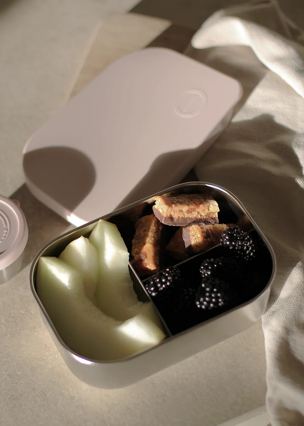 AYA&IDA Lunch Box i Soft Rose 900 ml med tre rum, rustfrit stål og blødt silikone låg – en praktisk og stilren madkasse til børn.