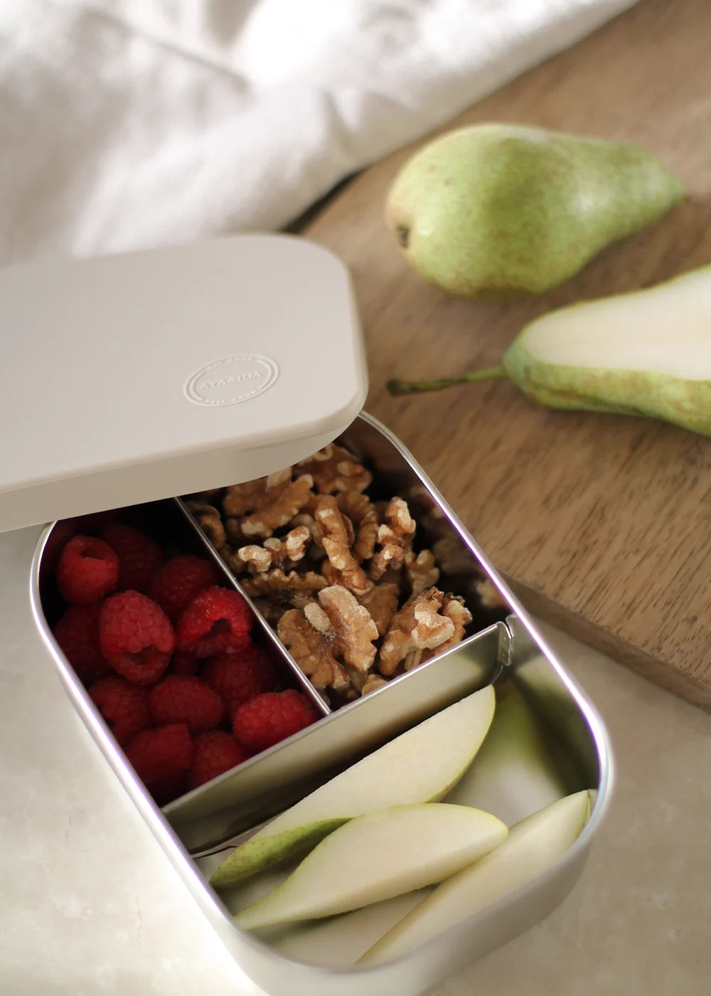 AYA&IDA Lunch Box i Cream Beige 900 ml med tre rum, rustfrit stål og blødt silikone låg – en praktisk madkasse til børn.