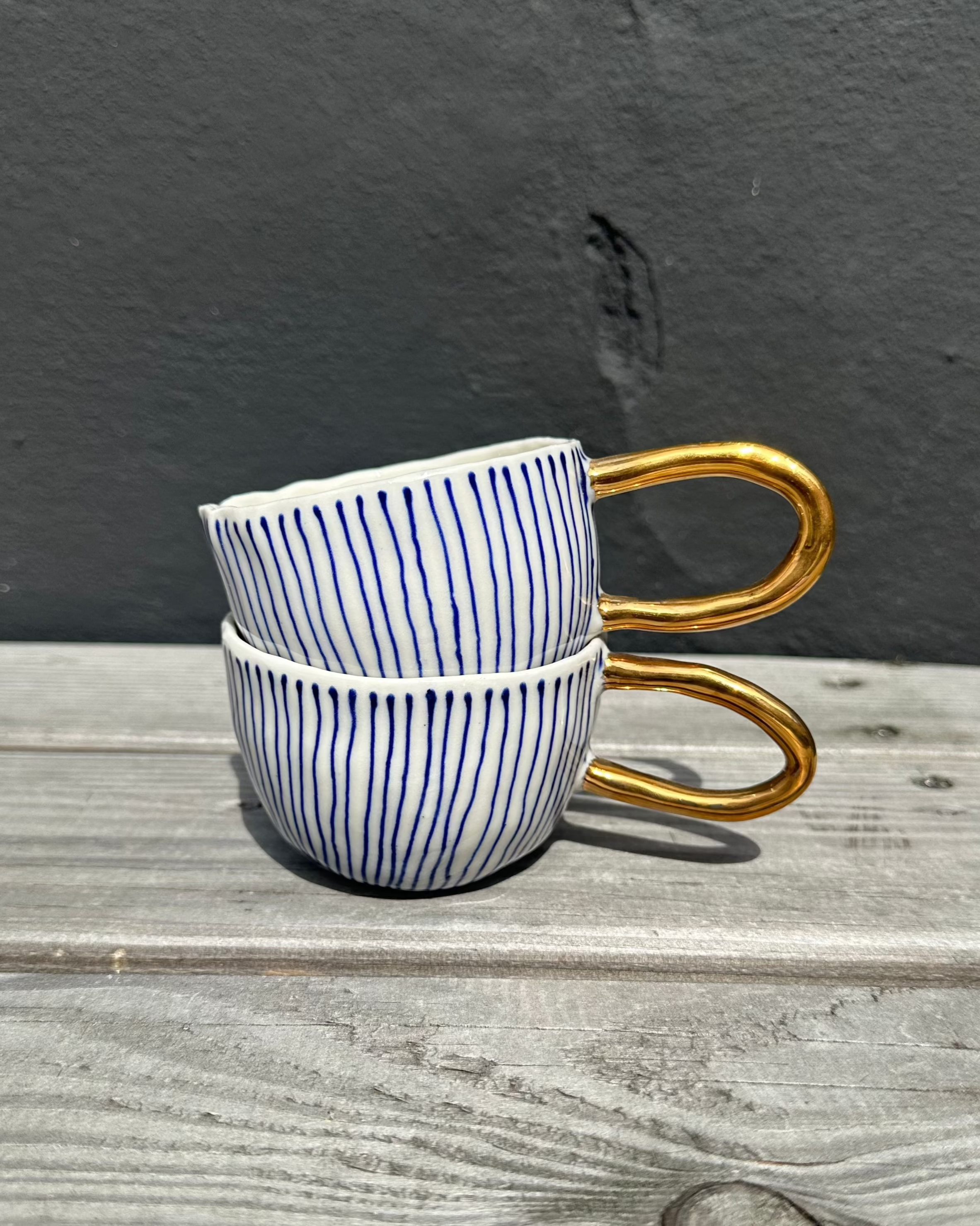 Christine Thuesen Vesterhavskop med tynde blå striber og guld håndtag – elegant og håndlavet porcelænskop til kaffe og te, ideel til borddækning og som gaveidé.