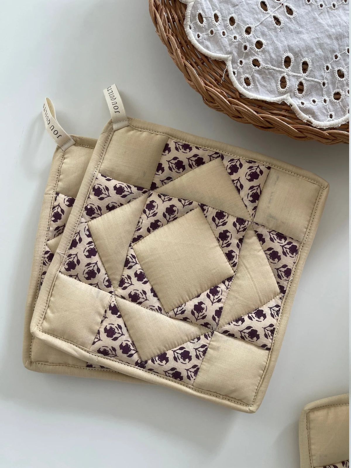 JOU Patchwork grydelapper 2 stk. i creme og mørk aubergine, håndsyet i 100% bomuld, 20x20 cm – køb hos butikalrum.dk.