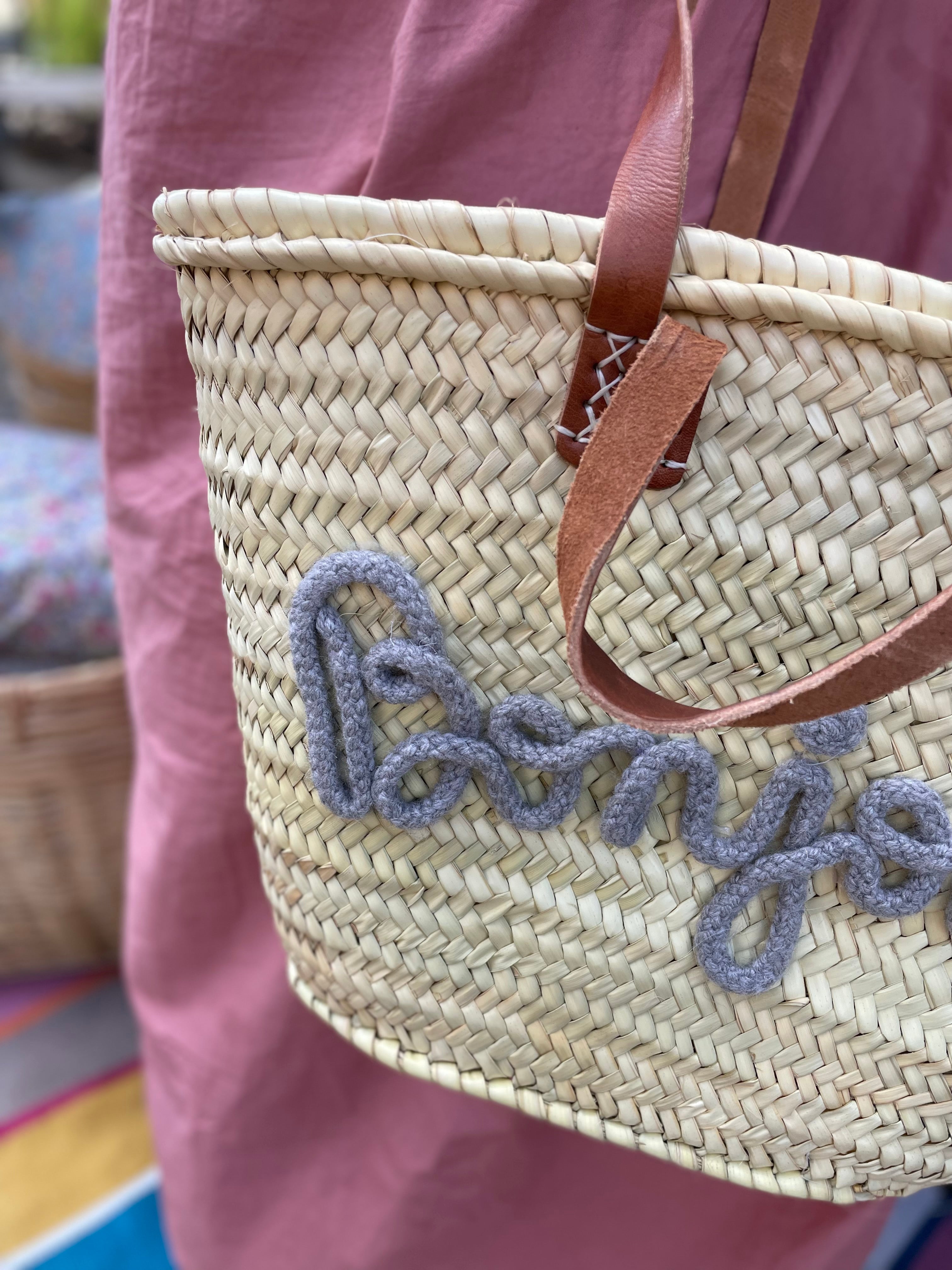 Lille flettaske med brune hanke og grå Bonjour tekst samt praktisk lukkepose indeni – køb hos Butik Alrum på Amager eller online på butikalrum.dk.