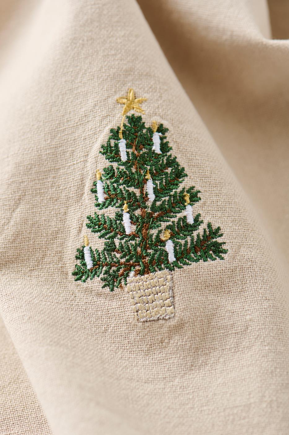 Hørfarvet stofserviet Tradition med broderet juletræ i kurv og hvide lys – køb hos butikalrum.dk.