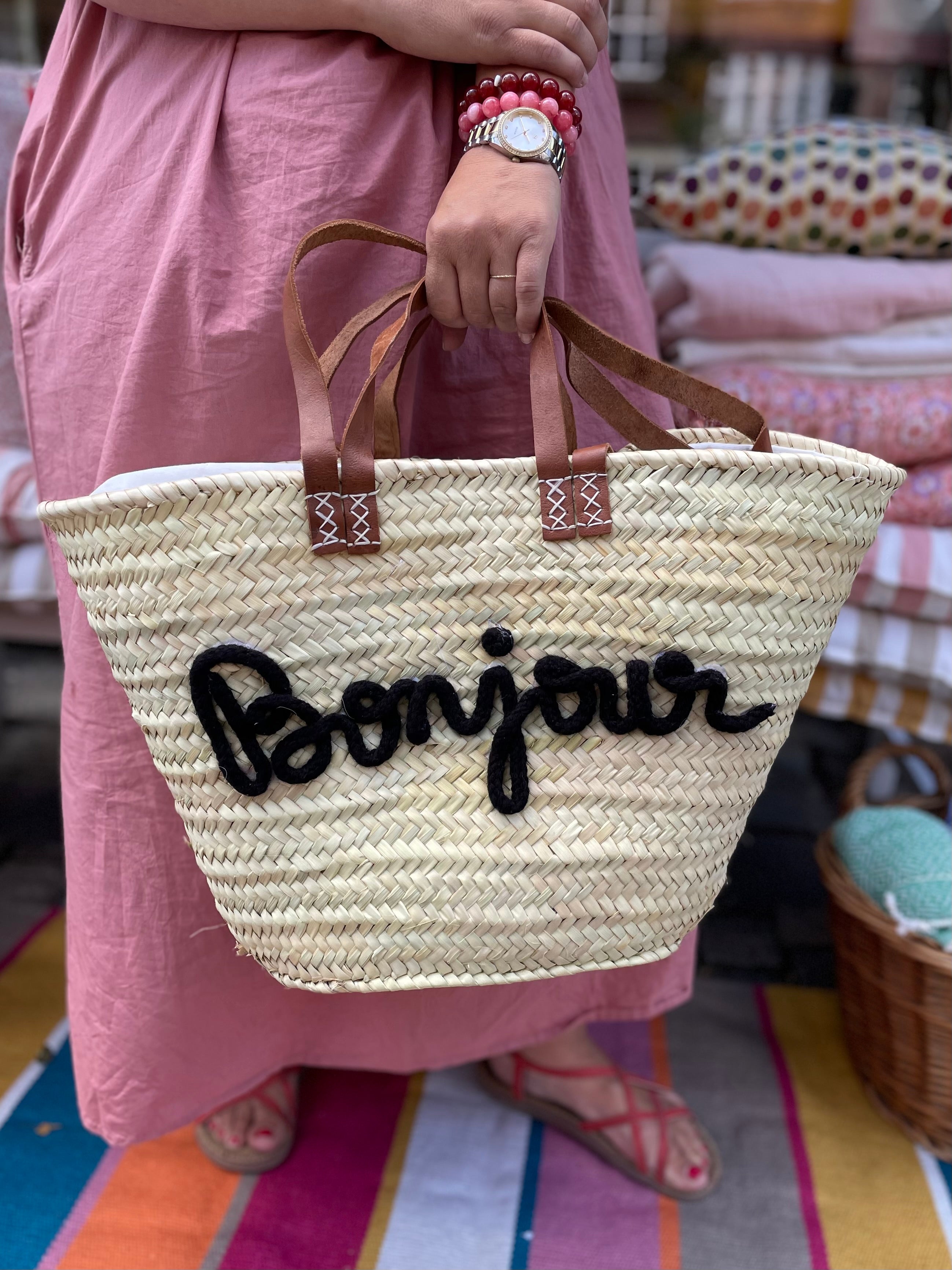 Stor flettaske med brune hanke, sort Bonjour tekst og praktisk lukkepose indeni – køb hos Butik Alrum på Amager eller online på butikalrum.dk.